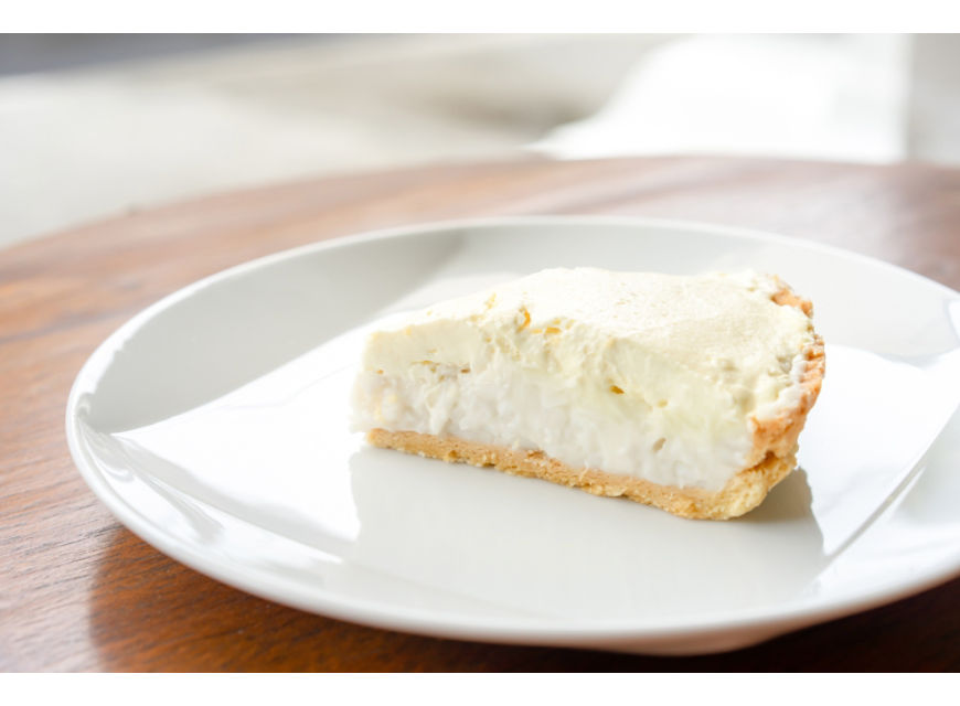 Clear Coconut Cream Pie in the dish on the wood table without anything topping on it. Shooting in the sunlight.