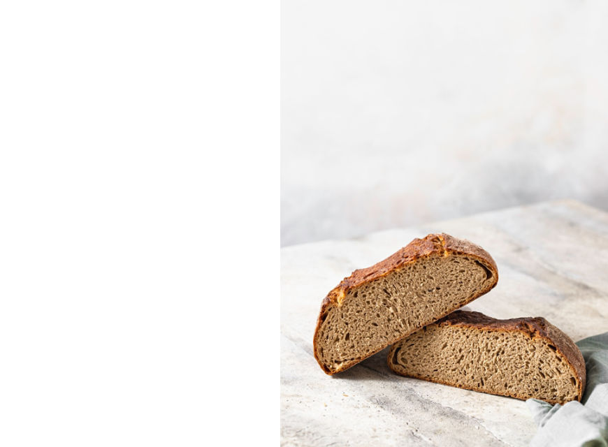 Freshly baked rye bread on a light concrete background, linen napkin. Place for your text. Freshly baked sourdough bread. Pastry items. Selective focus