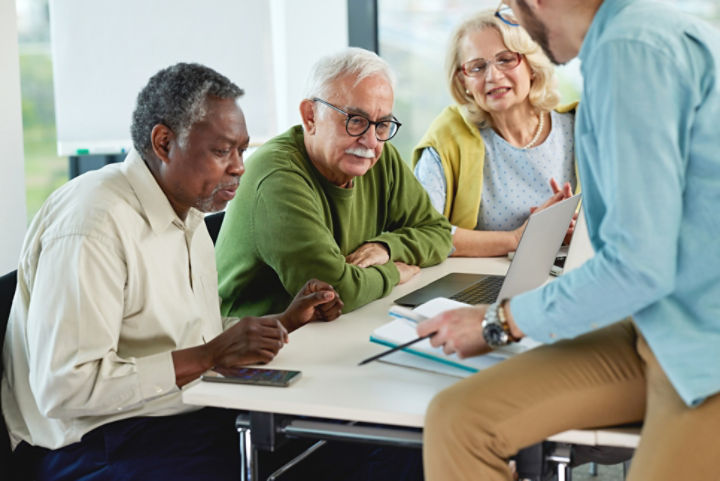 Seniors sitting at a table and looking at a computer