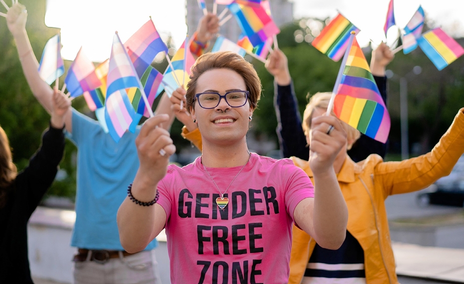 youth waving flag, wearing t-shirt with words, "gender free zone"