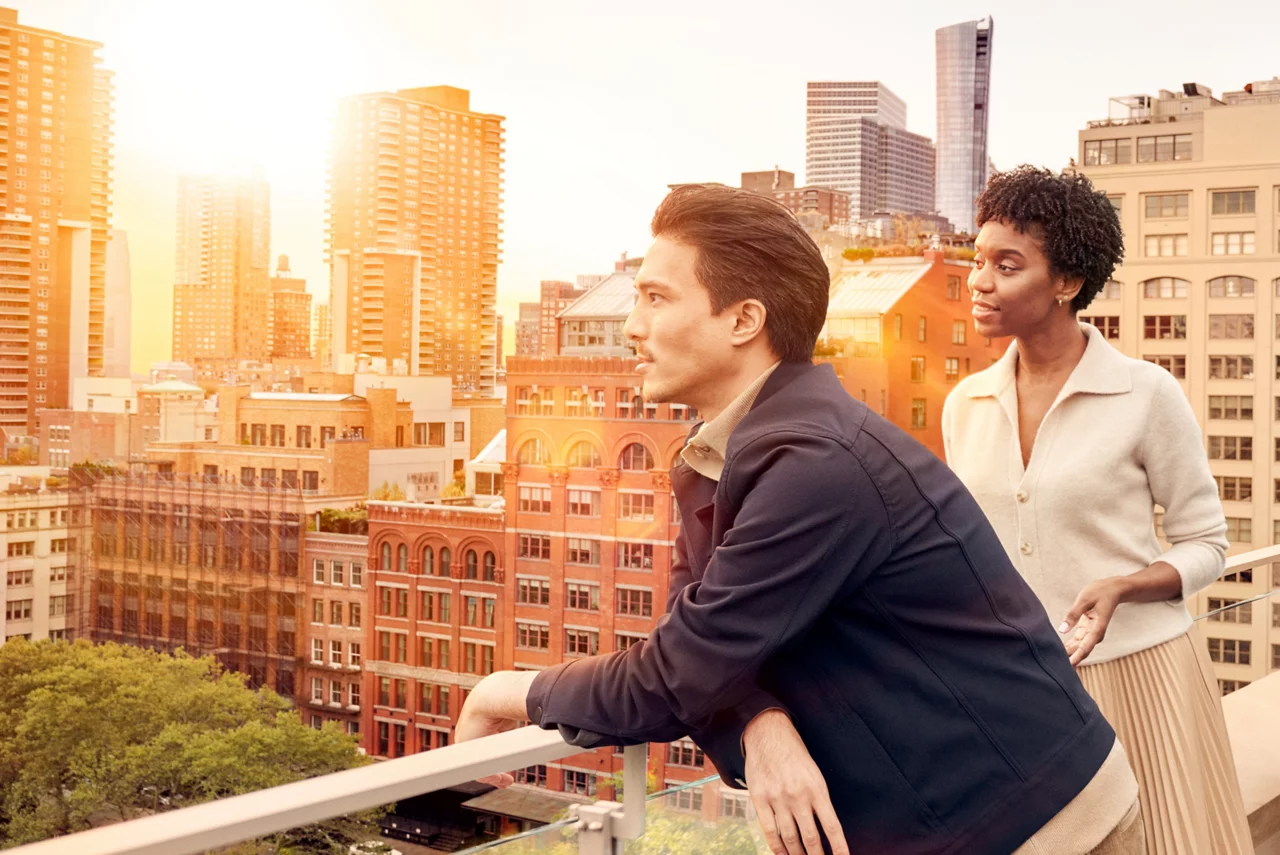 Deux professionnels debout sur un toit, contemplant un panorama urbain au coucher du soleil