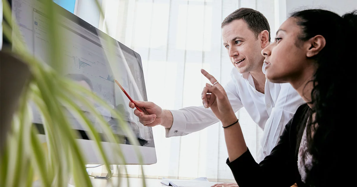 Man and woman discussing data on a large computer screen