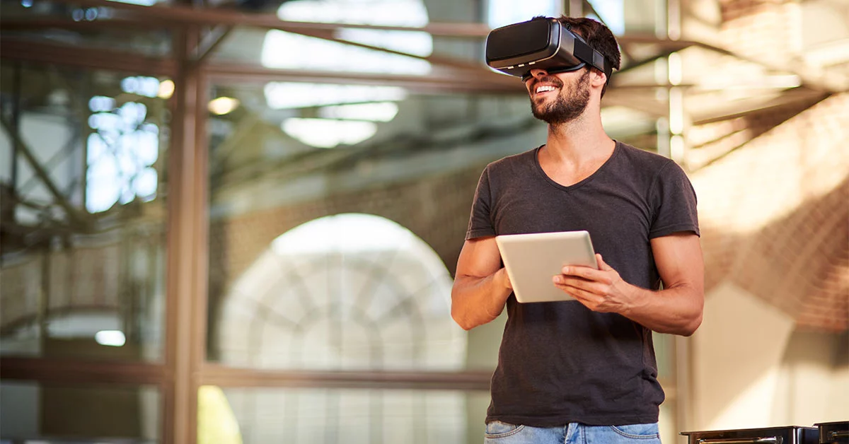 Man wearing virtual reality headset holds a tablet
