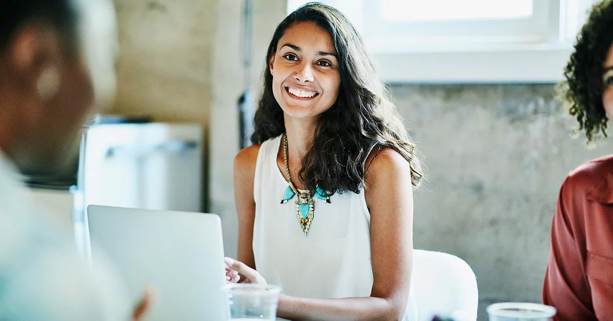Smiling businesswoman in discussion with colleagues during meeting in office conference room