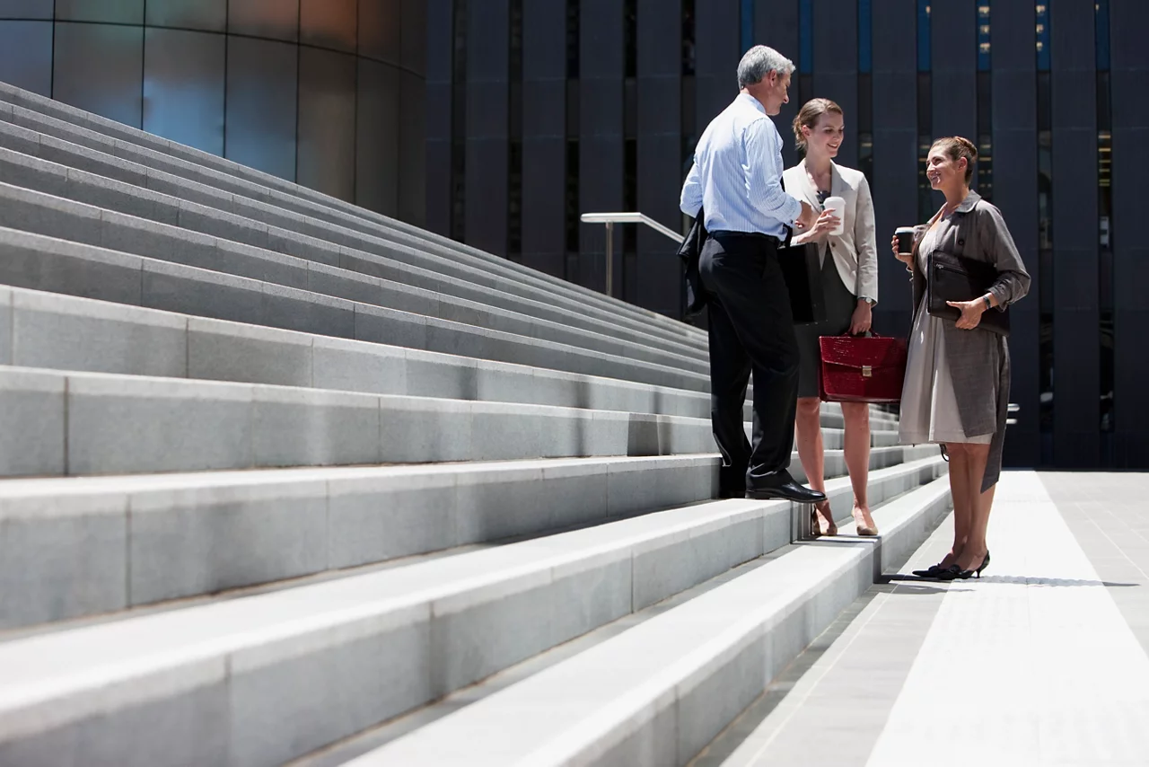 Two people walking outdoors in a business area ,with the office building in the background