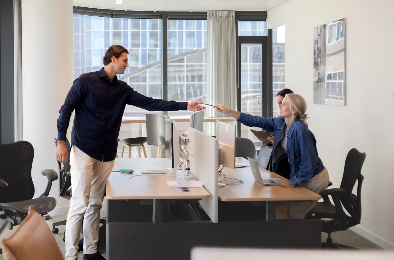 Twee zakenmensen die elkaar de hand schudden over moderne kantoorbureau's in een heldere werkplek met stadsgezicht.