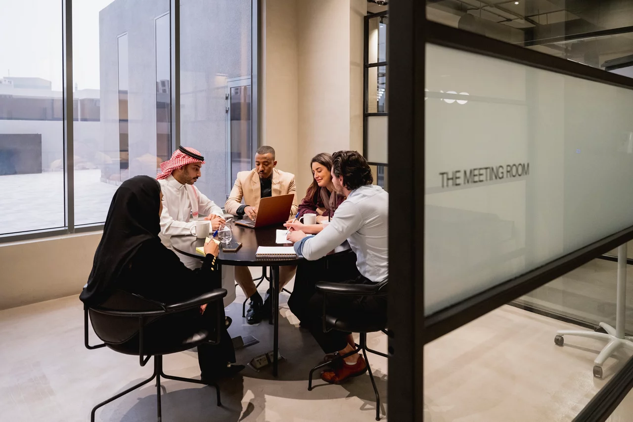 رجال ونساء سعوديون جالسون في غرفة اجتماعات