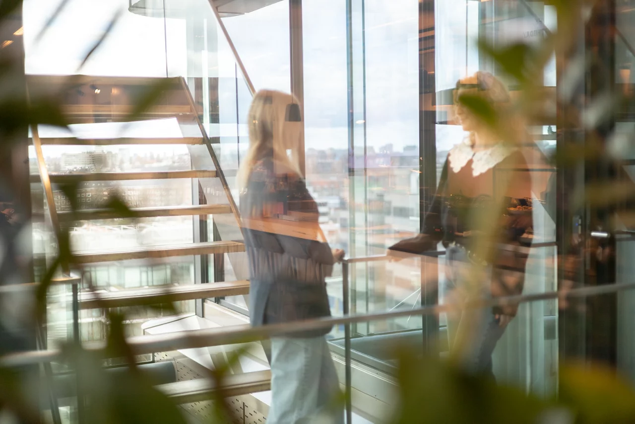 Female entrepreneur walking with disabled colleague while business executives discussing in background at workplace