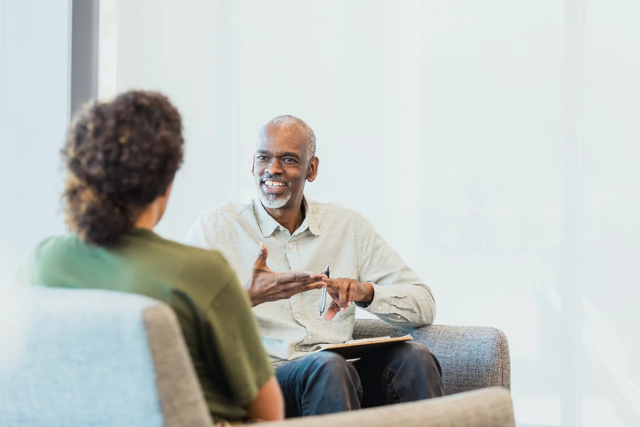 A woman listens the male counselor gestures and speaks
