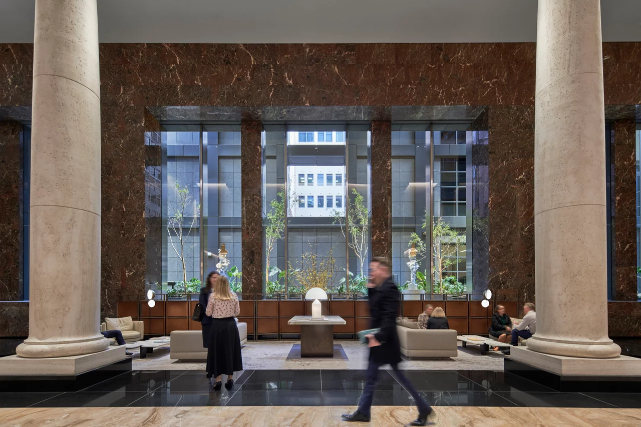 Spacious, modern office lobby with tall marble columns and polished stone floors.