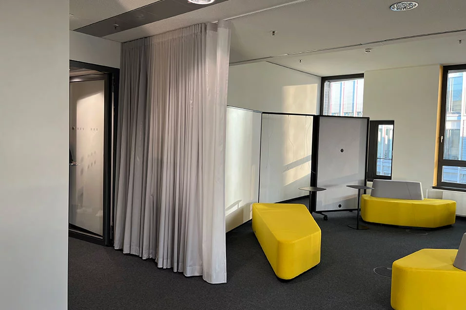 A room featuring yellow chairs and a white curtain, creating a bright and inviting atmosphere.