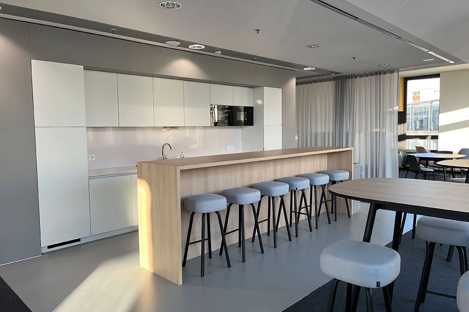 A sleek modern office interior showcasing a bar area with stools, designed for informal gatherings and collaboration.