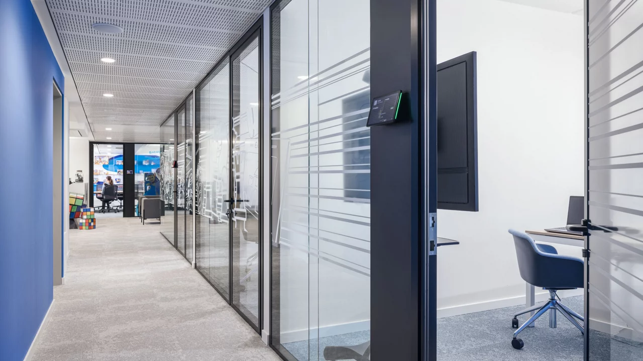 A stylish office with glass walls and a modern desk, highlighting a professional and airy workspace atmosphere.