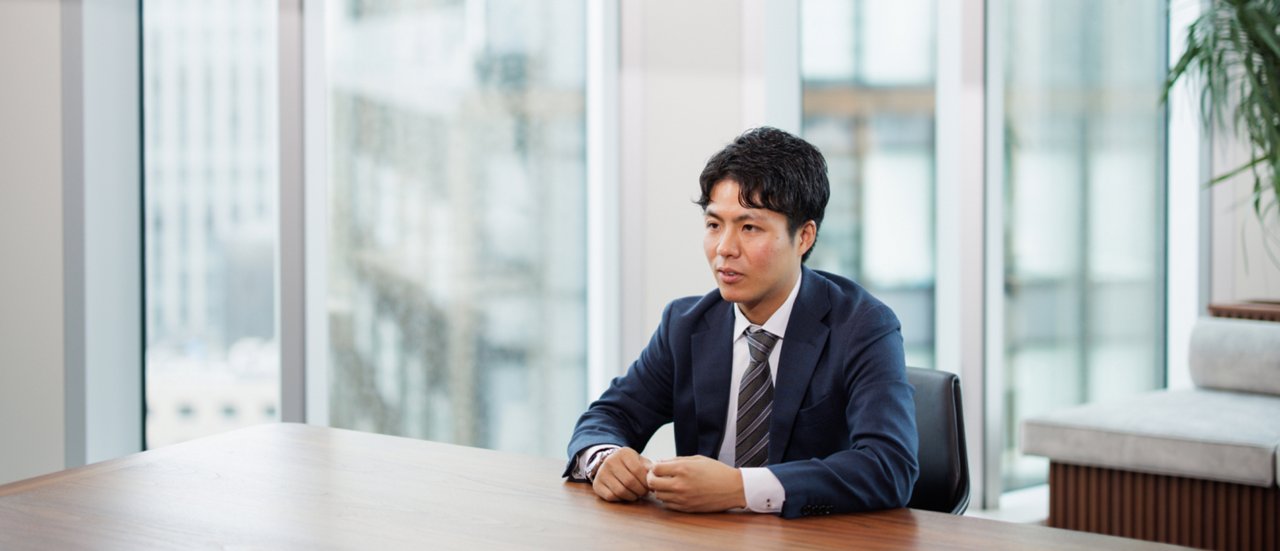 大きな窓のある近代的なオフィスの会議テーブルに座っているネイビーのスーツを着たプロのアジア人ビジネスマン