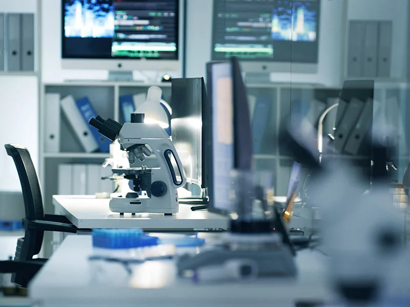 A microscope is positioned on a lab desk