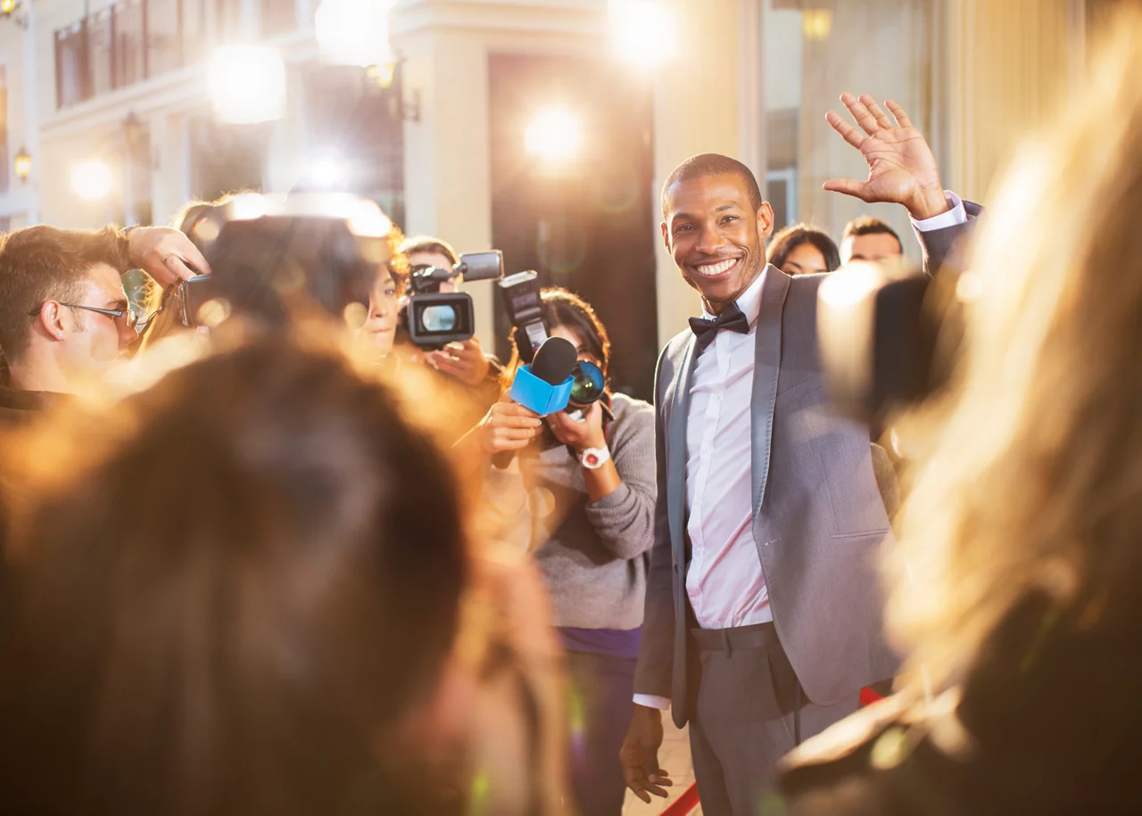 A young man smiling and waving towards camera