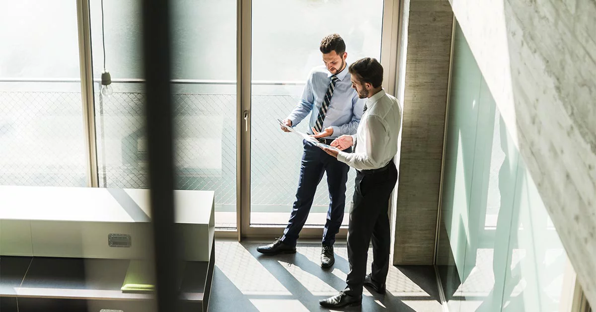 Two men in business suits standing in a modern office