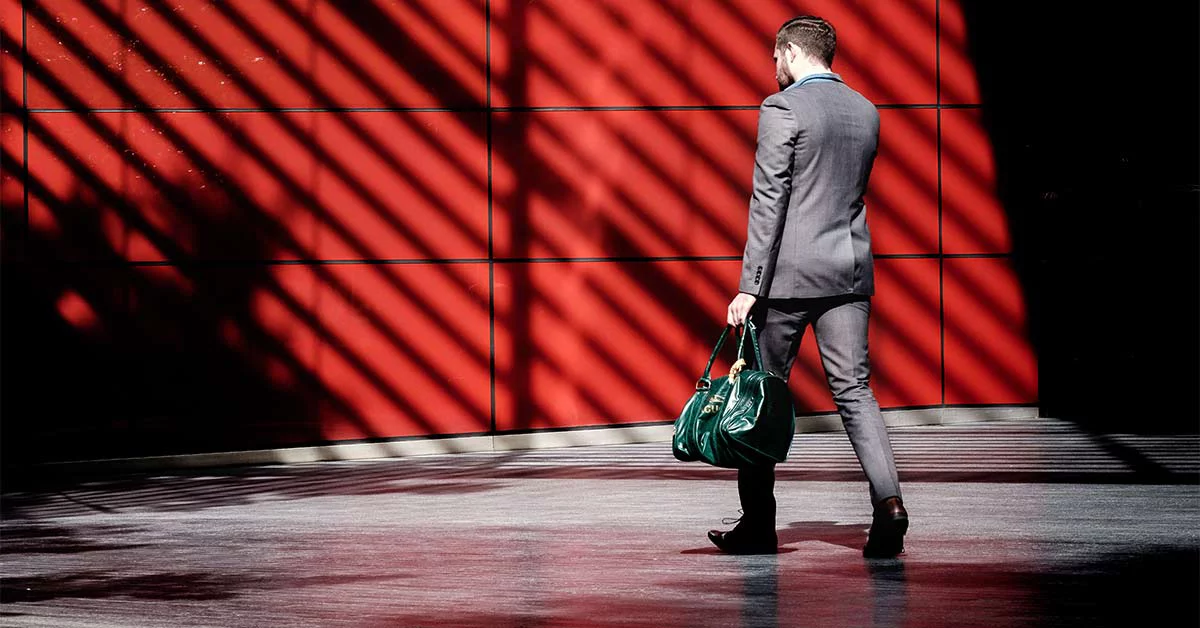A man in a suit walks past a vibrant red wall