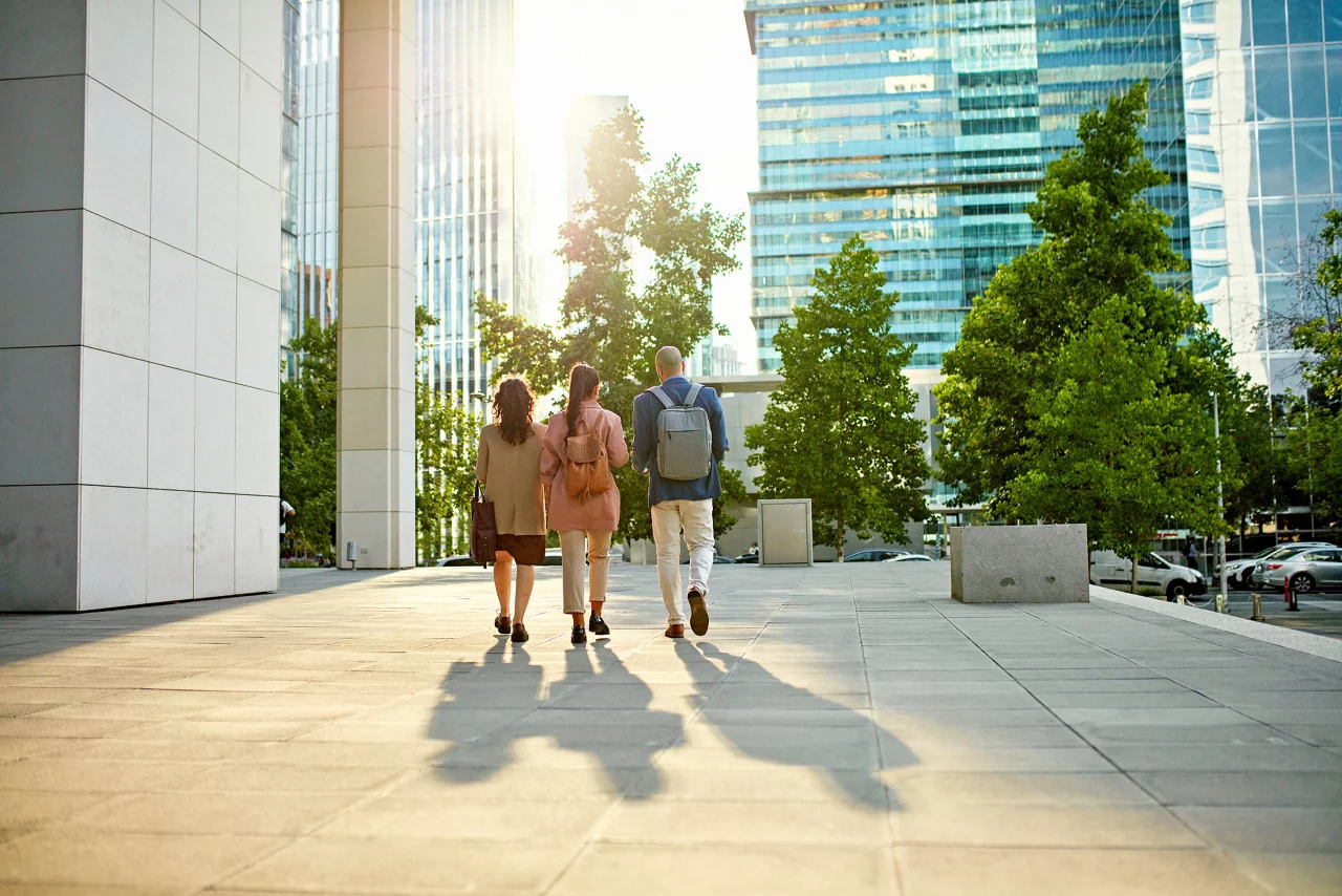 Full length rear view of male and female professionals walking across business park esplanade.