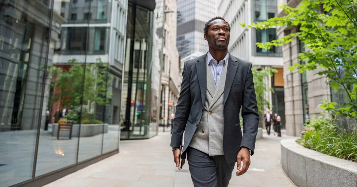 Businessman going to meet a client in a busy city. He is walking outdoors on a cloudy day.