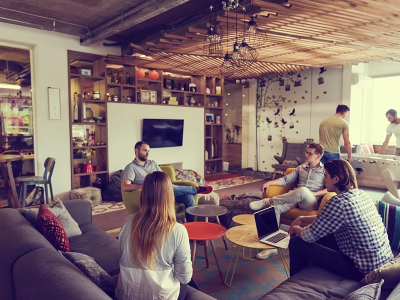 A group of people gathered in a cozy living room, engaged in conversation and enjoying each other's company.