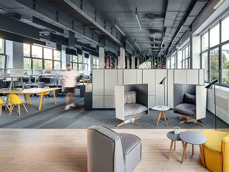 An open office space featuring yellow chairs and tables arranged for collaborative work.