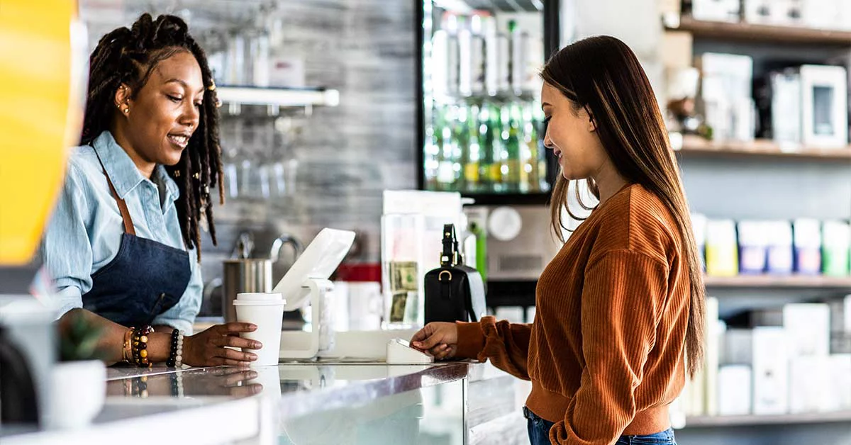 Young woman using credit card reader at coffee shop counter