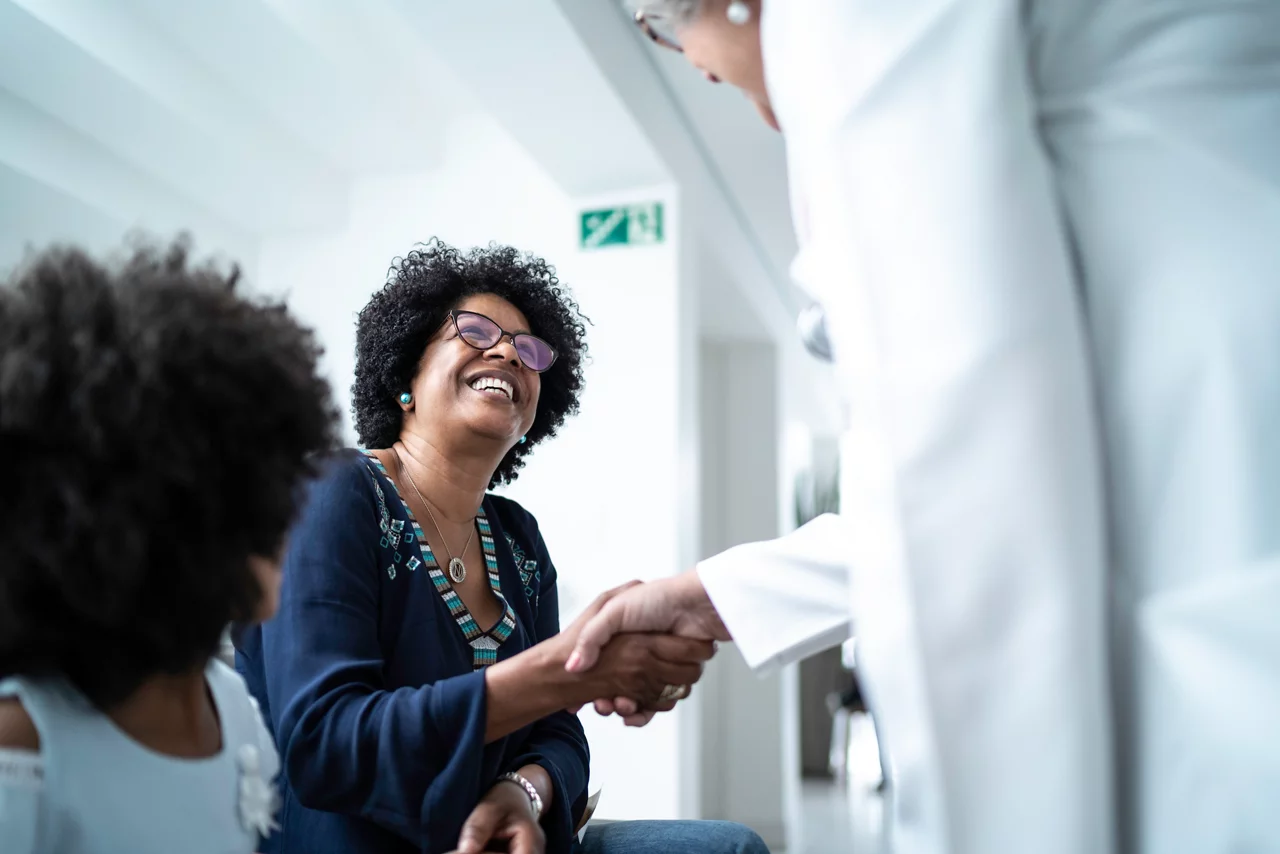 Female senior doctor welcoming / greeting mother and daughter at hospital