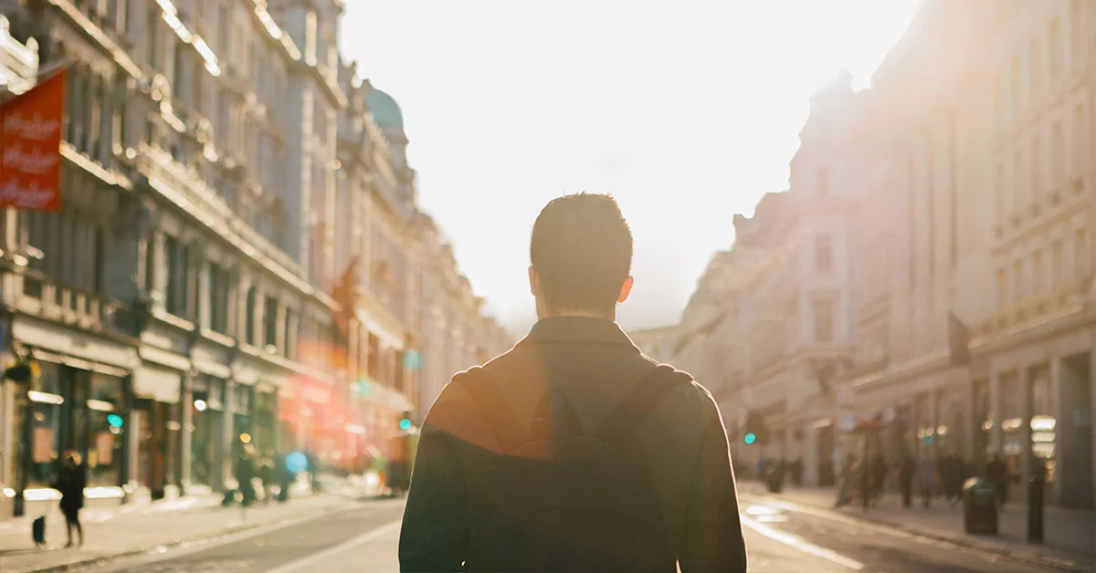A man walks down a street carrying a backpack