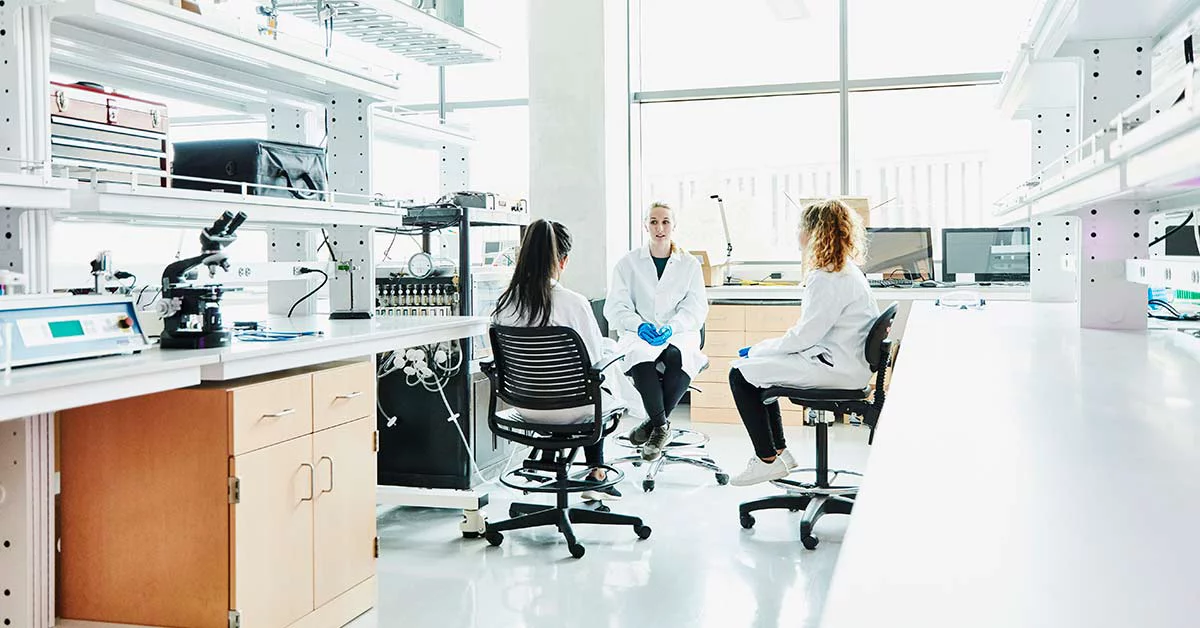 Three individuals in lab coats seated at workstations