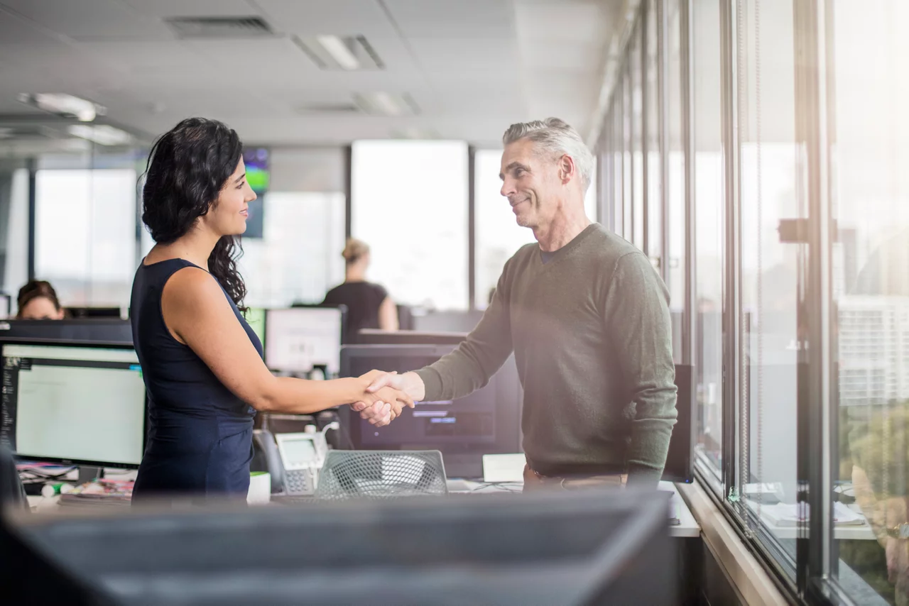 Casual business people shaking hands after closing a deal in the office.