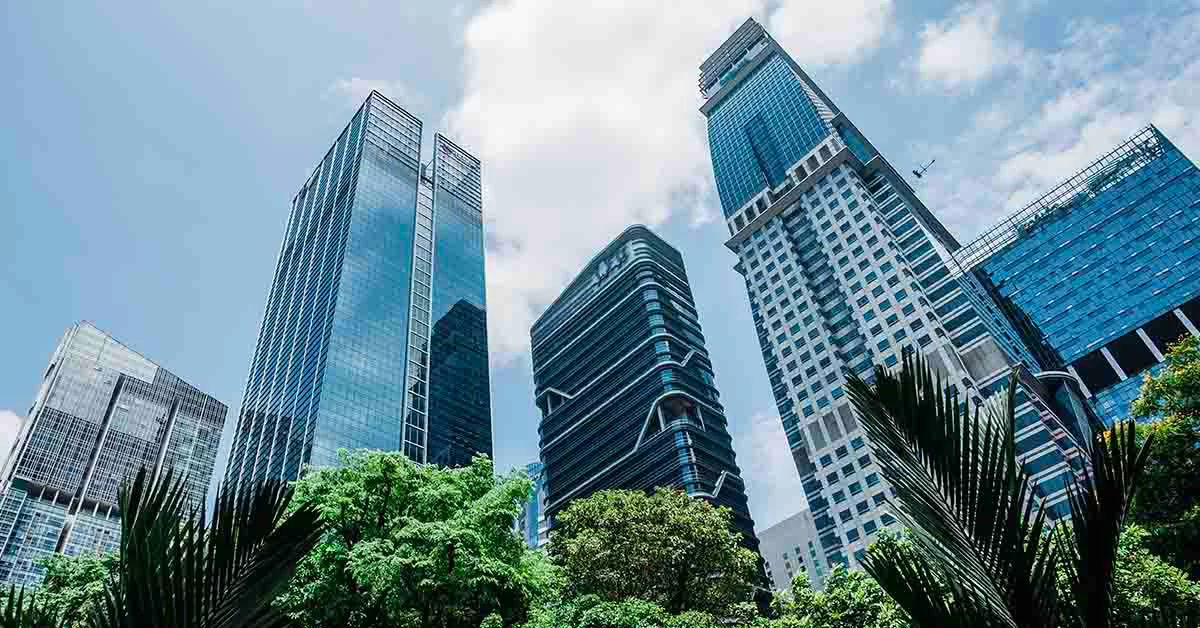 Five tall glass skyscrapers frame by some green trees below them