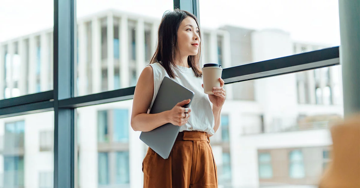 A woman stands and having a cup of coffee