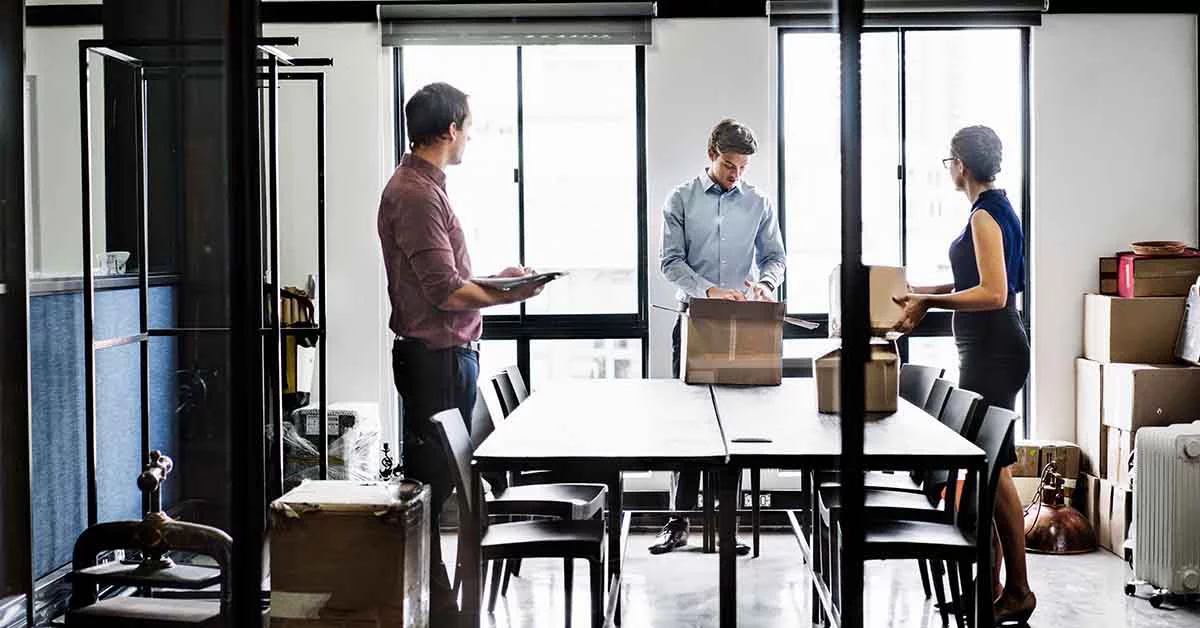 Two men and a woman unpacking boxes in an office