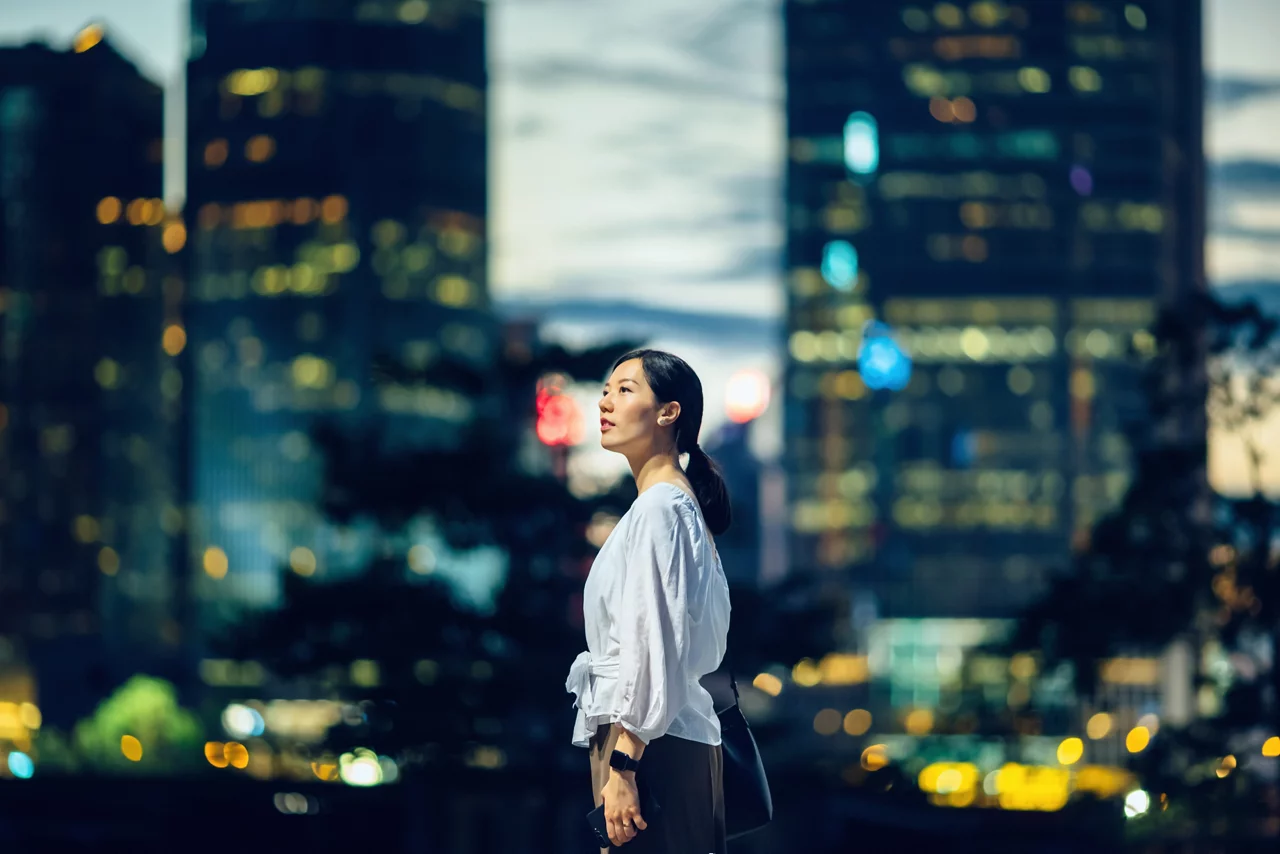 woman standing against illuminated city buildings