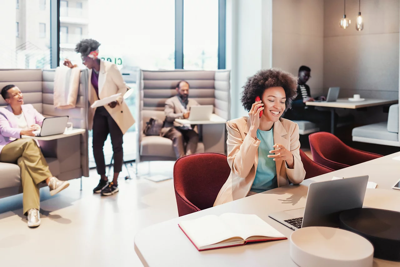 Business woman talking on smart phone while working in a co-working space