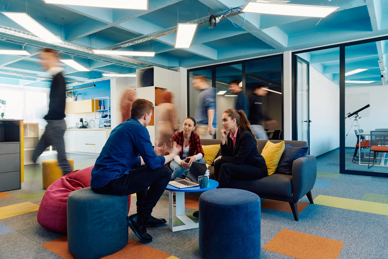 Multiethnic startup business team on meeting in a modern bright open space coworking office. Brainstorming, working on laptop. Group of coworkers walking around in motion blur.