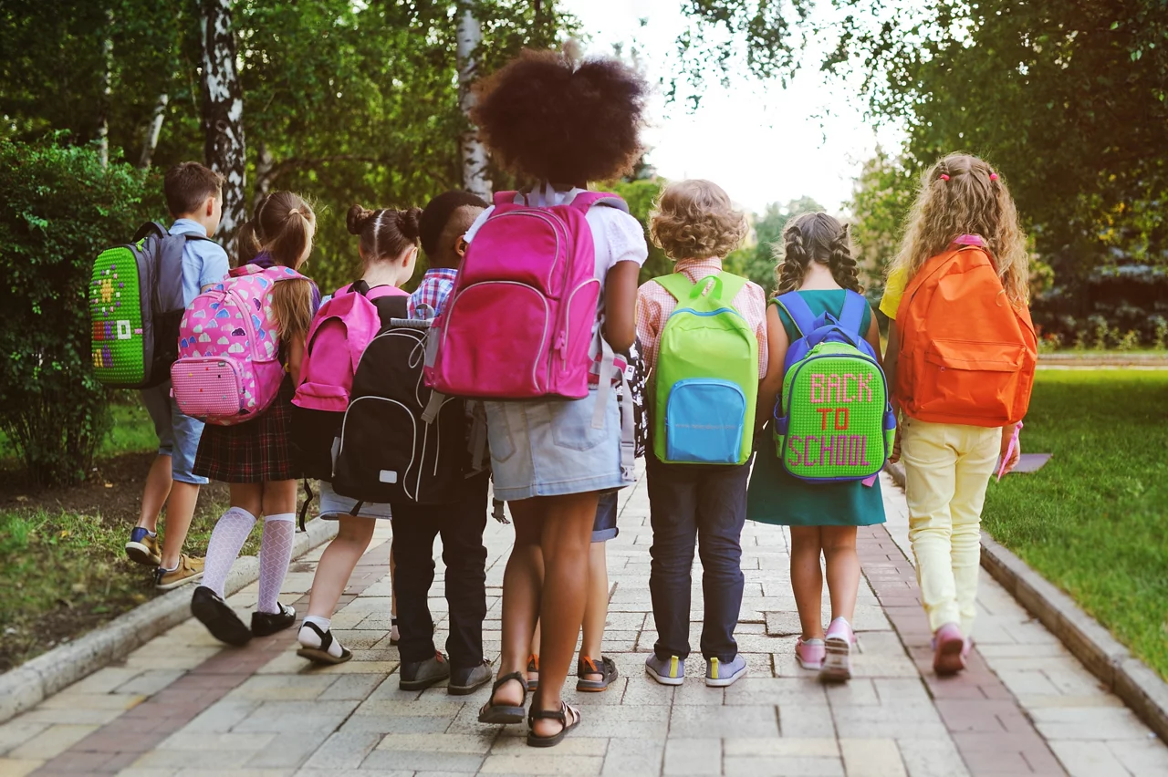 Small schoolchildren with colorful school bags and backpacks run to school