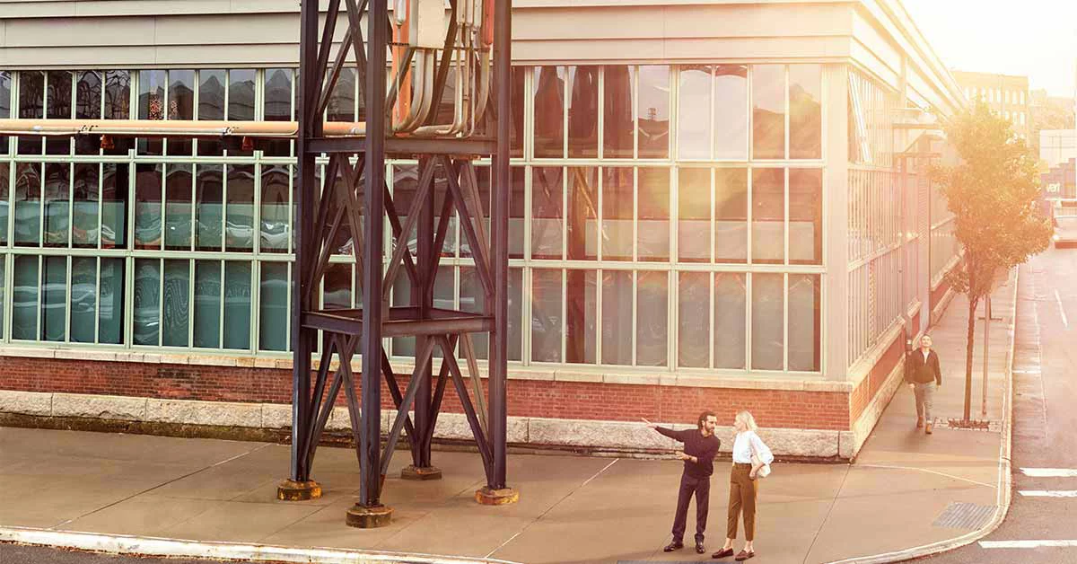 Two people talking in front of the glass building