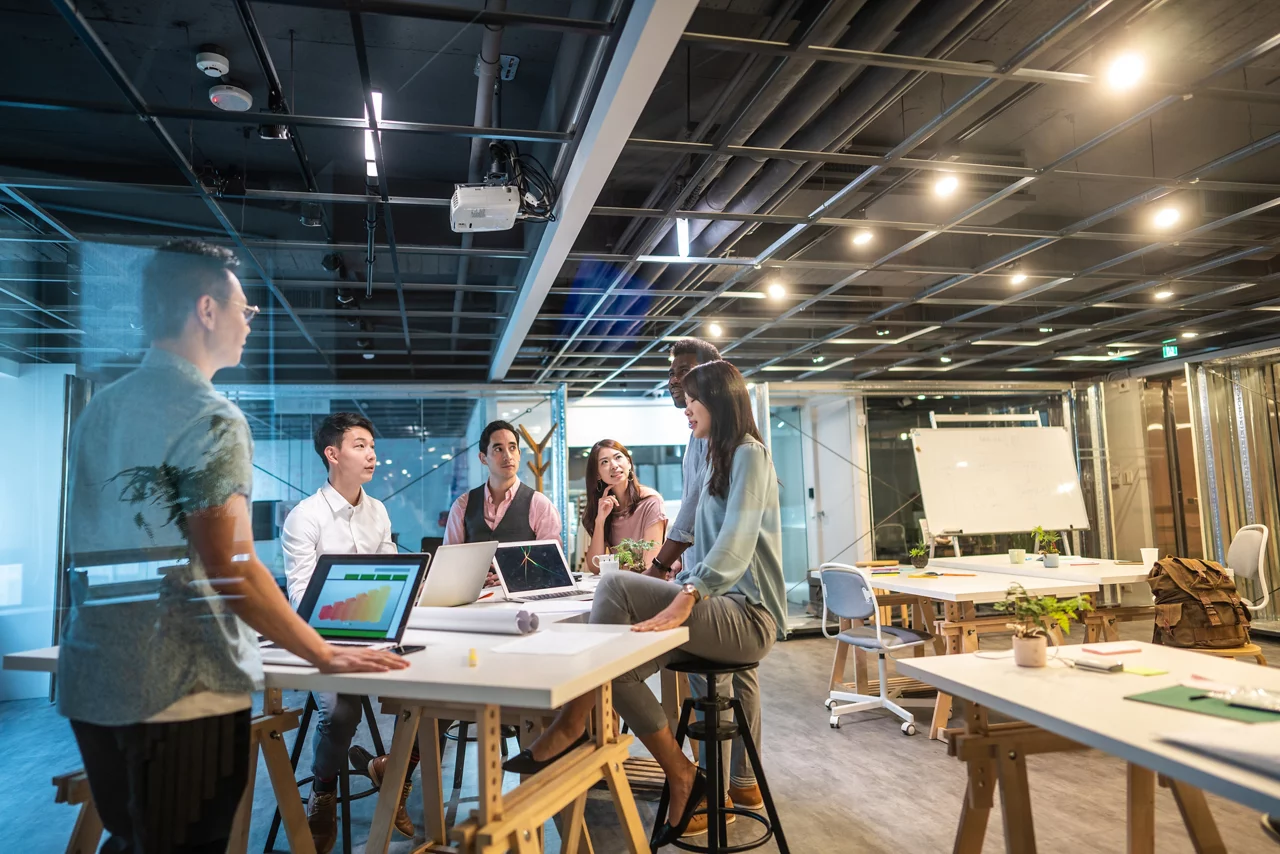 Group of young, modern people sitting on business meeting in modern coworking space and suggesting ideas for the best business strategy