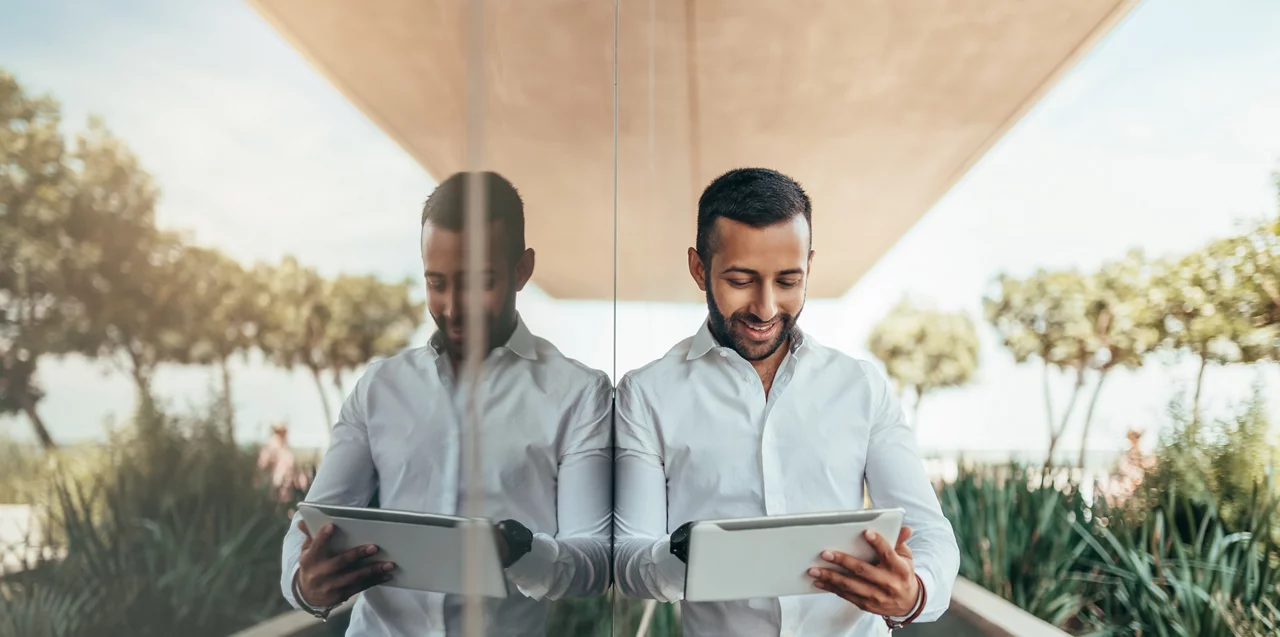Indian businessman standing outside building with a tablet