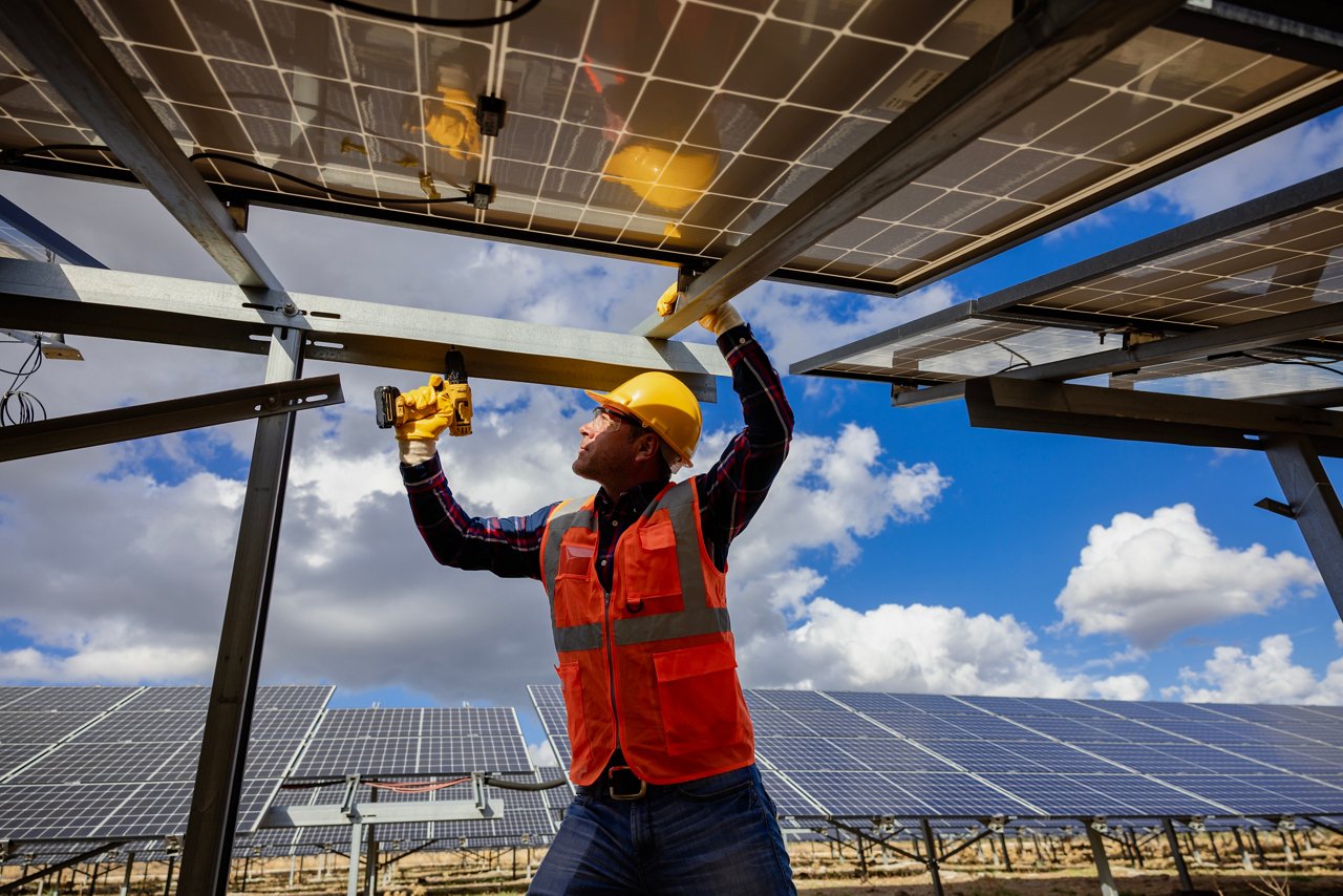 Worker using a power drill to work on a solar panel 