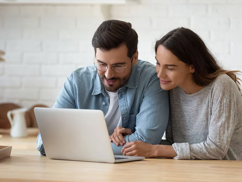 a man and a woman looking at a laptop screen
