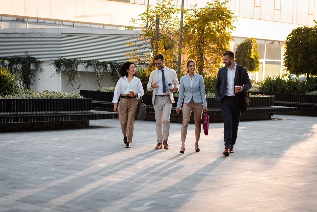Group of business people walking outside in front of office buildings.