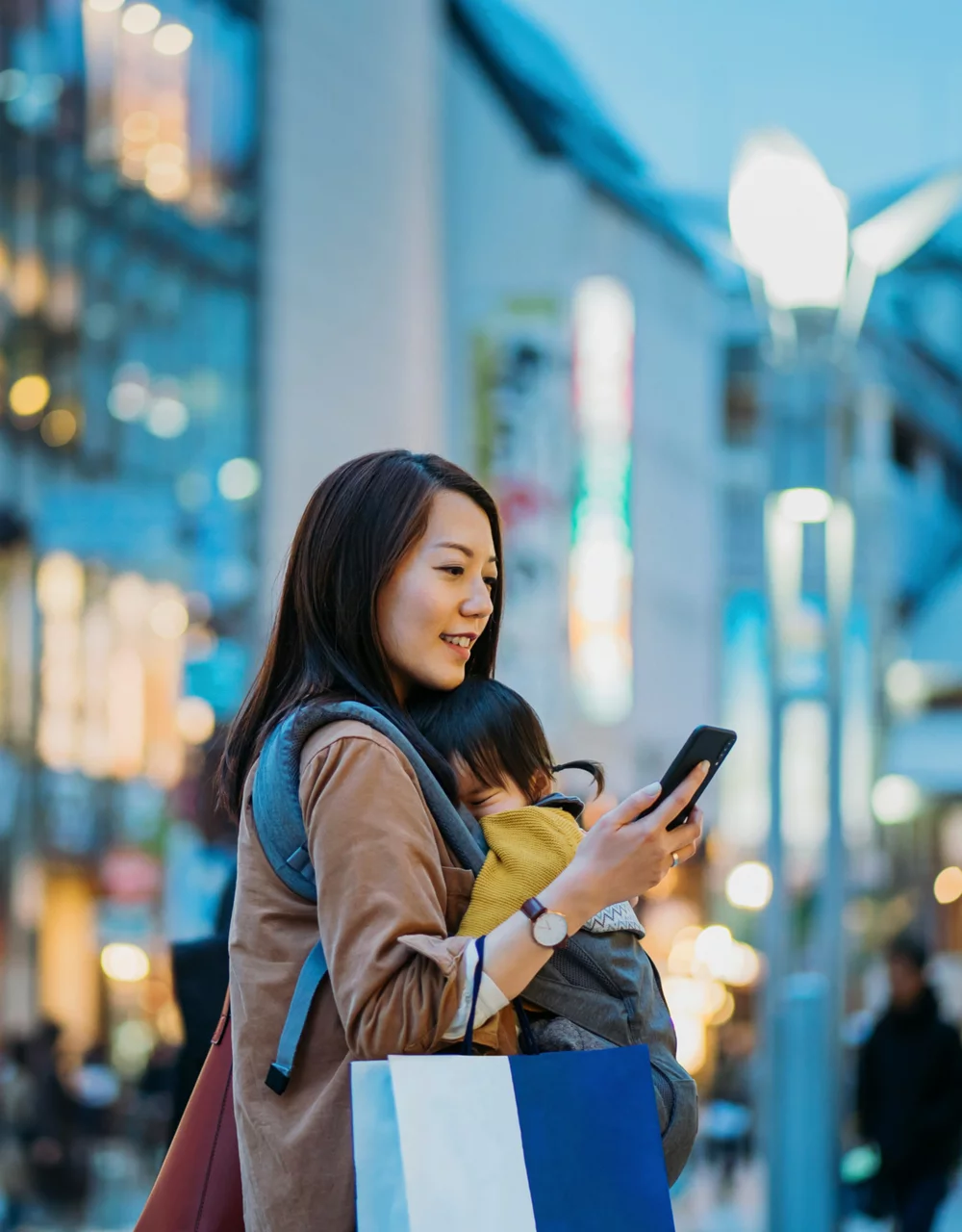 Women checking phone in a street with her baby