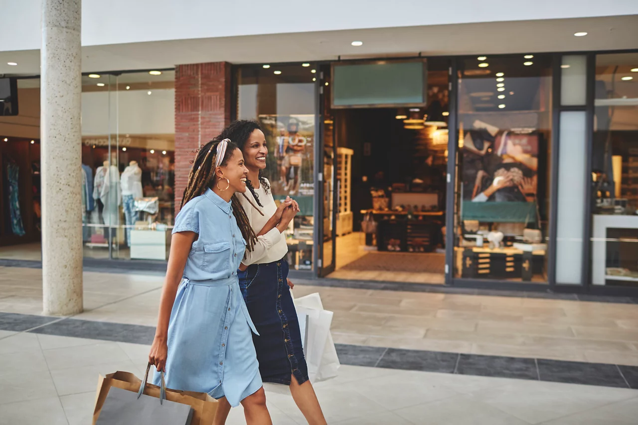 Happy women friends walking with shopping bags in shopping mall