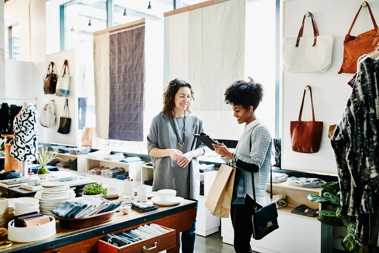 Smiling customer completing transaction on digital tablet in boutique shop