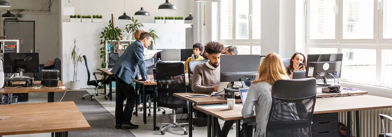 Escritório open space, com pessoas trabalhando diante de computadores