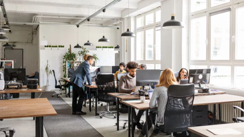 Escritório open space, com pessoas trabalhando diante de computadores
