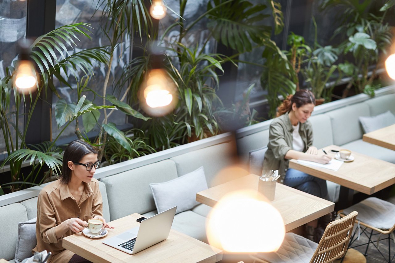 ABW型オフィス内のカフェスペースで働く従業員